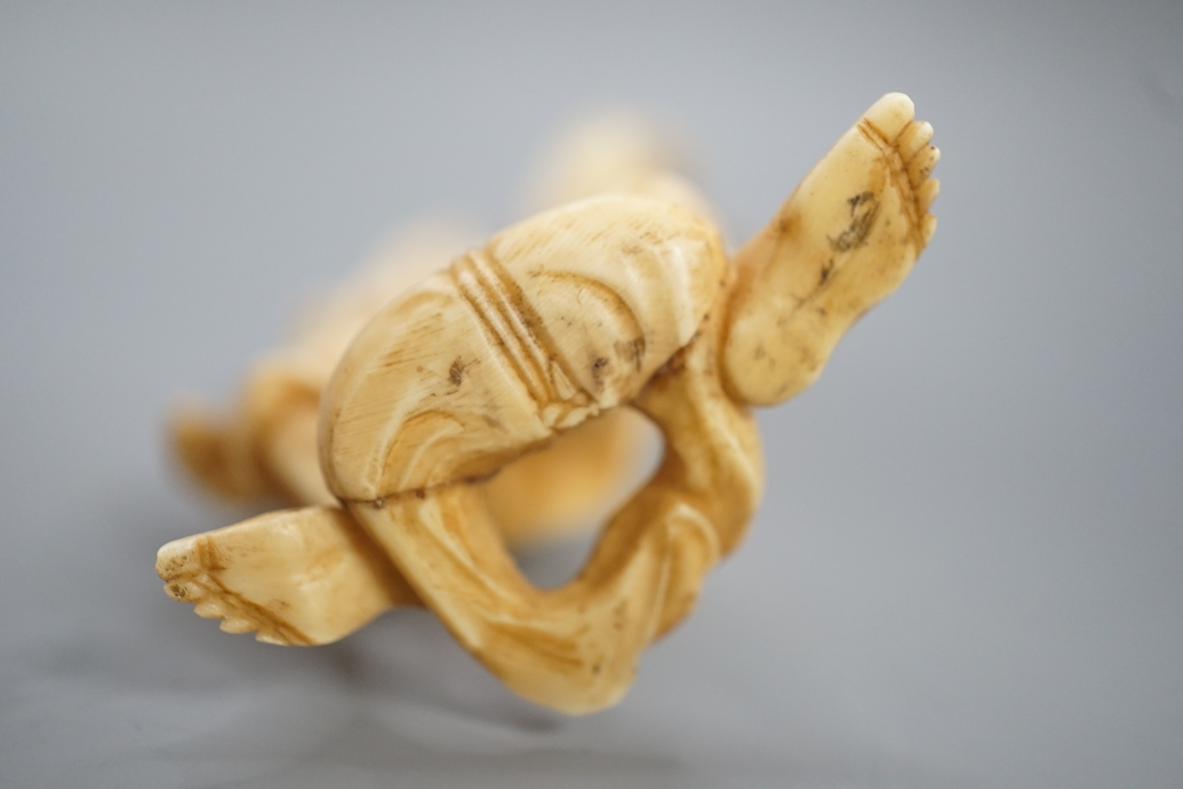 A Japanese ivory okimono of a man holding a monkey which is being attacked by an eagle, early 20th century 15.5cm